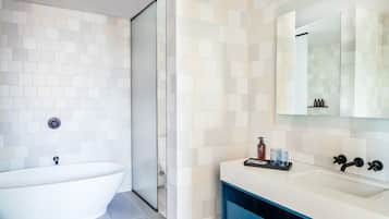 A modern bathroom with a freestanding bathtub, a sink with a mirror, and a shower area.