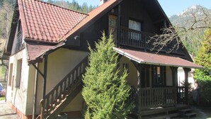 A wooden house with a steeply pitched roof, a balcony, and a staircase leading to the entrance.