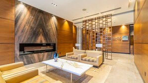 A modern lobby with a marble wall, a reception desk, and a seating area with a sofa and armchairs. - Modern Apartments in North York (Toronto)