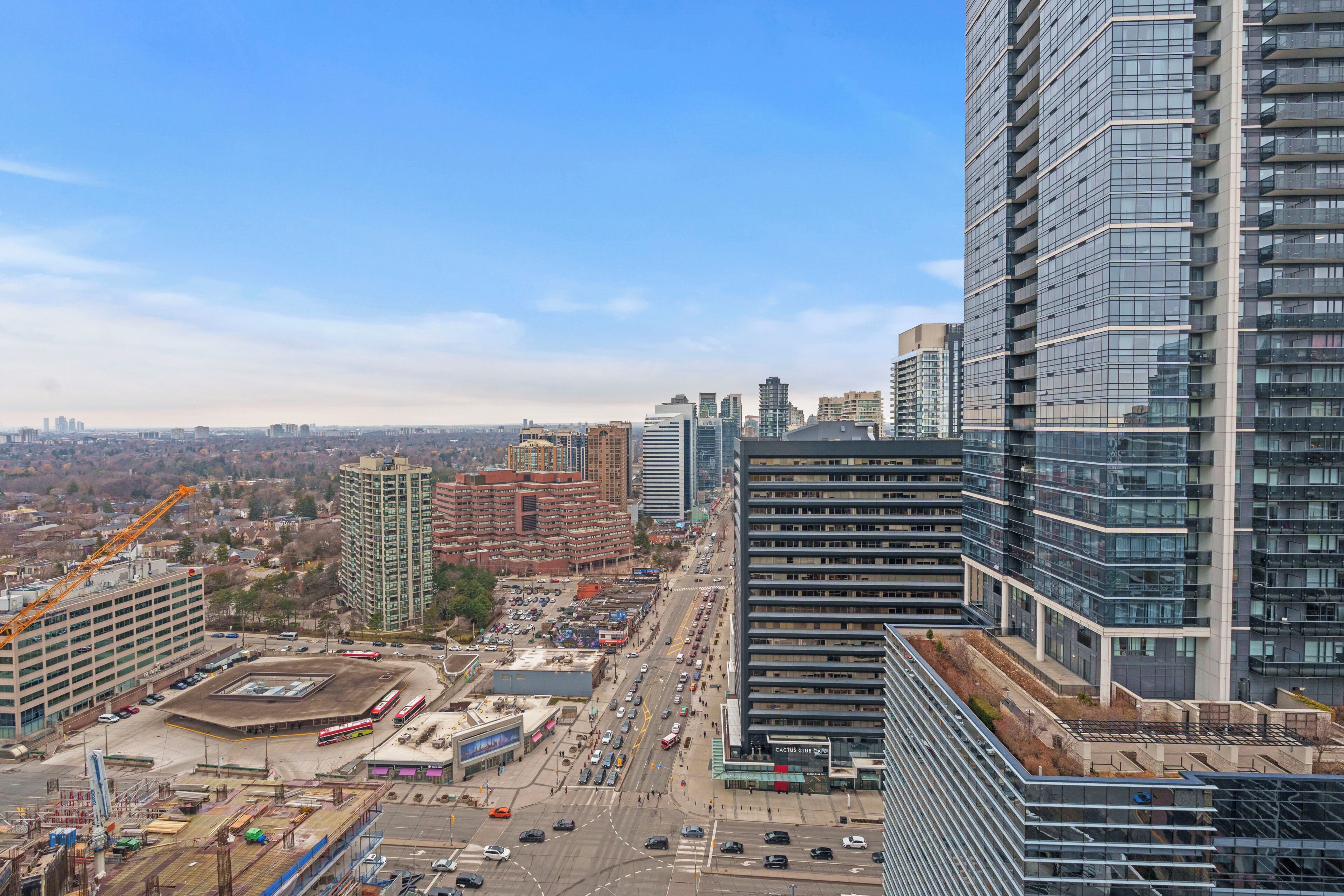 A high-rise building with a modern glass facade, surrounded by other high-rise buildings and a busy street with construction.