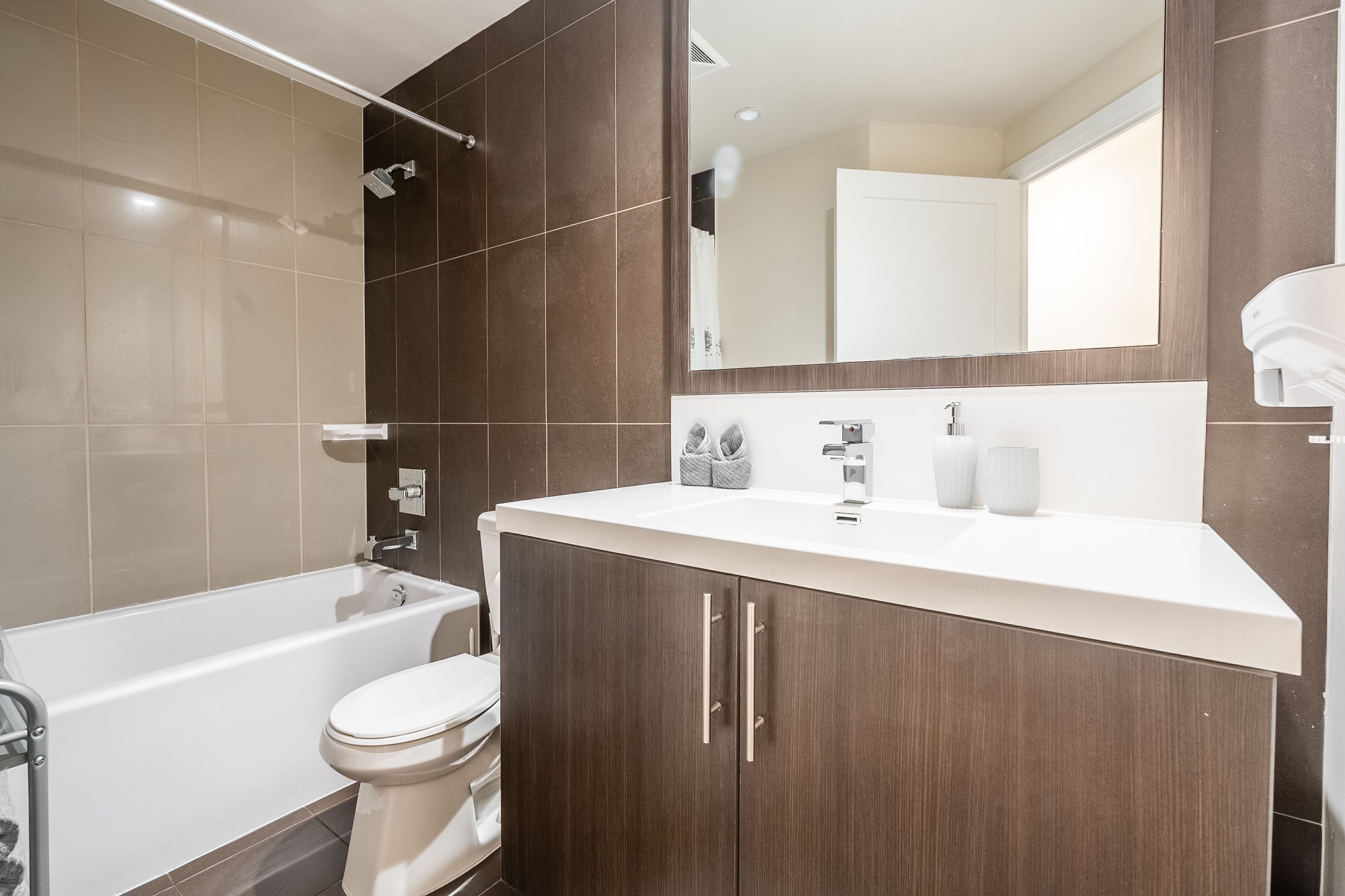 Une salle de bain moderne équipée d’une baignoire, de toilettes, d’un meuble-lavabo et d’un grand miroir.