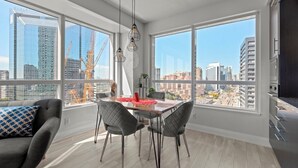 A modern kitchen with large windows, a dining area with a table and chairs, and a view of the cityscape. - Modern Apartments in North York (Toronto)