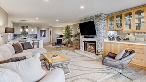 A modern living room with a fireplace, a kitchen with wooden cabinets, and a dining area. - Amelia Retreat C 3 - Hosted by Moore AI Rentals (Fernandina Beach)