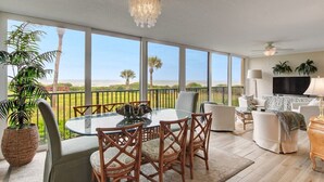 A spacious balcony with a glass table and chairs, a TV, and a ceiling fan. - Amelia Retreat C 3 - Hosted by Moore AI Rentals (Fernandina Beach)