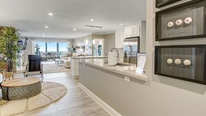 A modern kitchen with a central island, white cabinetry, and a dining area with a round table and chairs. - Amelia Retreat C 3 - Hosted by Moore AI Rentals (Fernandina Beach)