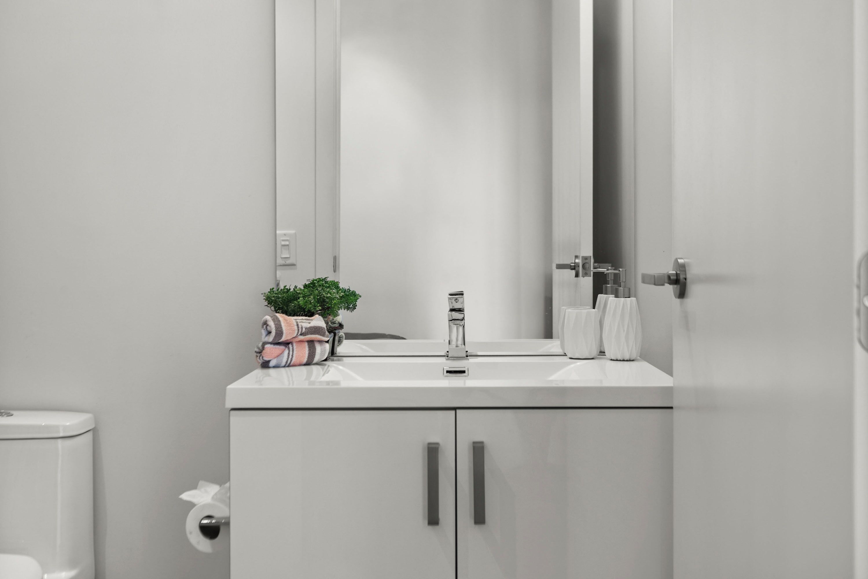 A modern bathroom with a white sink, a mirror, and a toilet.