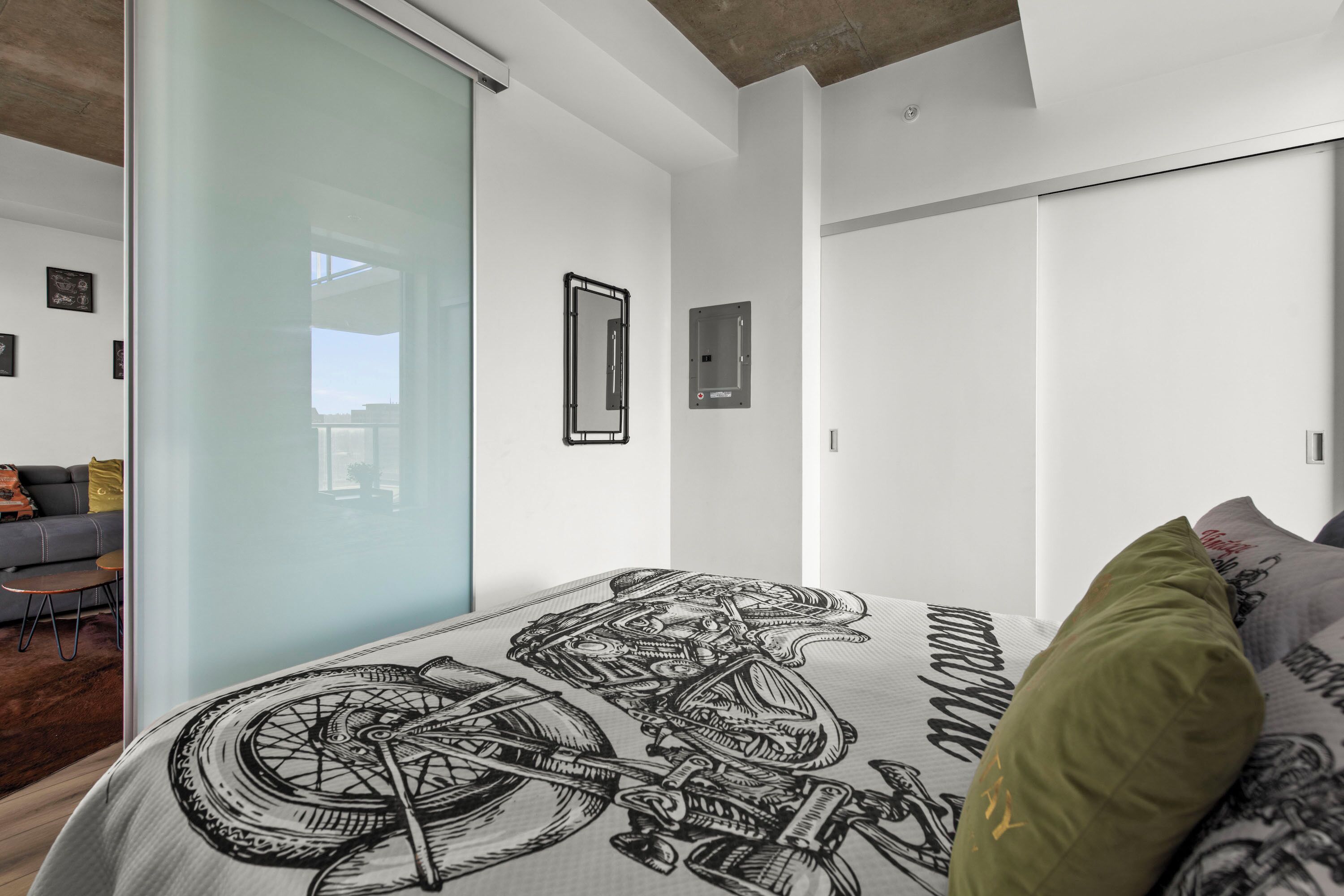 A modern bedroom with a large bed featuring a mechanical design, a sliding glass door, and a view of the outdoors.
