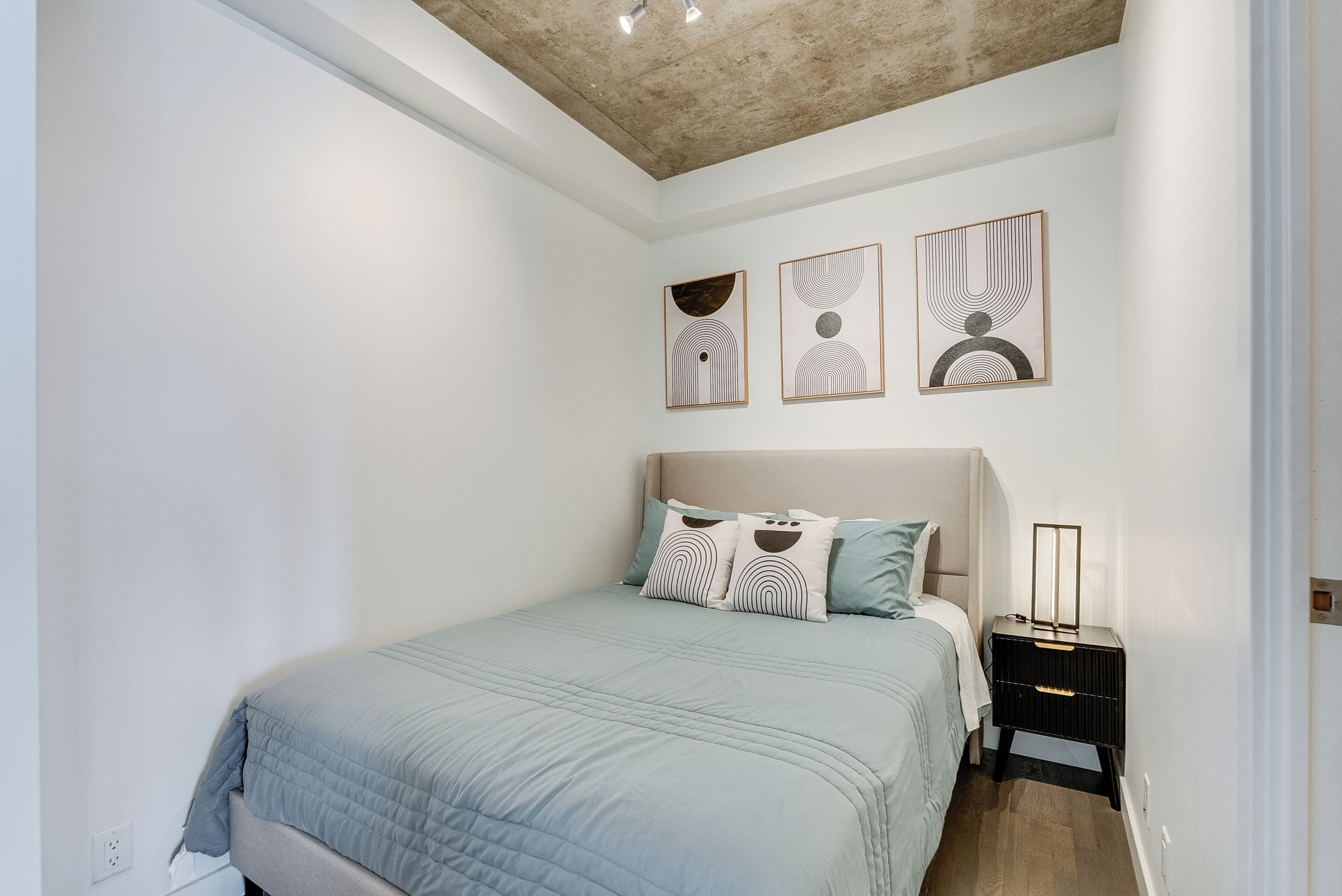 Un dormitorio con cama, mesita de noche y decoración en la pared.