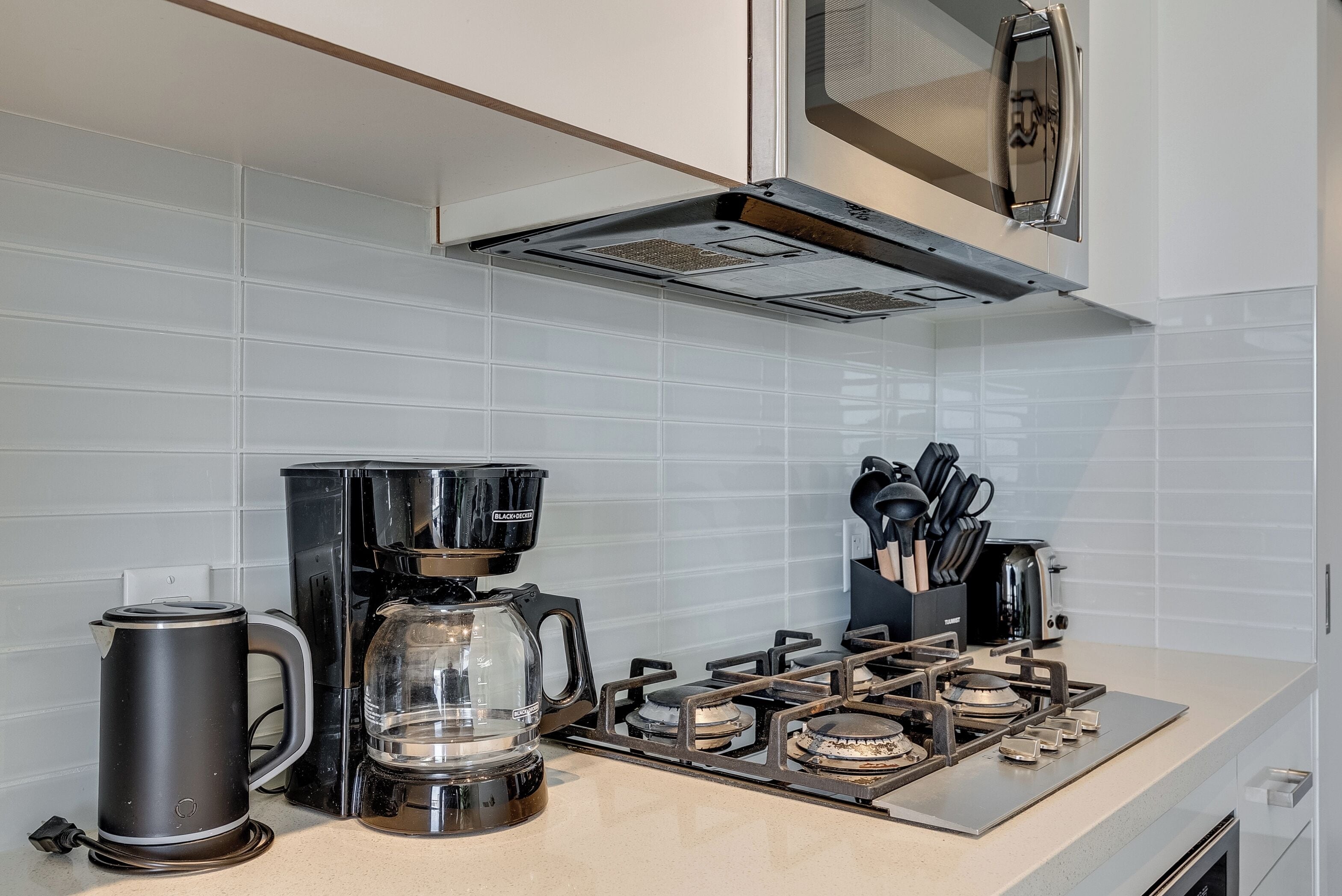 Una cocina con estufa a gas, cafetera y hervidor.