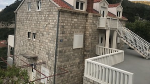 A stone building with a red-tiled roof, a balcony, and a staircase. - Comfortable 2 Bedroom Apartment (Mljet)