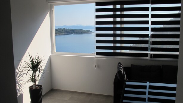 A room with a large window, a potted plant, and a chair. - Comfortable 2 Bedroom Apartment (Mljet)