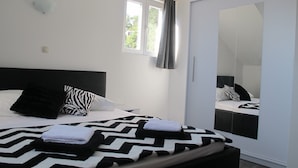 A bedroom with a bed, a mirror, and a window. - Comfortable 2 Bedroom Apartment (Mljet)