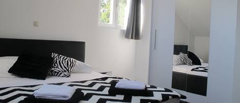 A bedroom with a bed, a mirror, and a window.