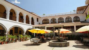 A courtyard with outdoor seating, arches, and a fountain.