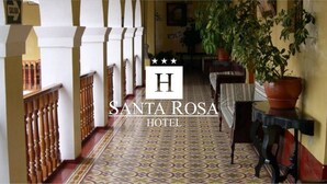 A hotel corridor with patterned flooring, wooden railings, and potted plants. - Hotel Santa Rosa (Ayacucho)