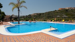A swimming pool with tiled deck, lounge chairs, palm trees, and a gazebo.