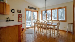 A kitchen with wooden cabinets, a dining table with chairs, a clock, and a sign reading "Welcome to the Mountains." - Golden Bear Inn (Davis)