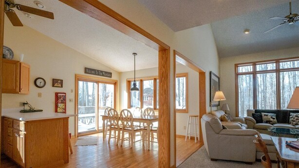 A spacious living area with a wooden dining table and chairs, a sofa, and a large window offering a view of trees. - Golden Bear Inn (Davis)