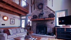 A cozy living room with a fireplace, a television, and a comfortable seating area. - Hemlock Lodge (Davis)
