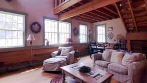 A spacious living room with wooden beams, large windows, and a high ceiling. - Hemlock Lodge (Davis)