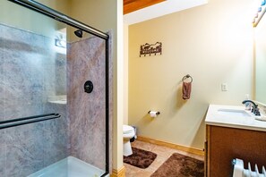 A bathroom with a shower, toilet, sink, and a welcome sign on the wall.