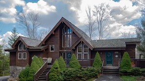 A wooden cabin with a stone foundation, a front porch, and a staircase leading to the entrance.