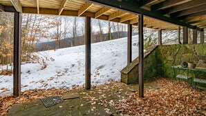 A covered outdoor area with a stone wall, a metal table, and chairs.
