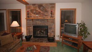 A living room with a stone fireplace, a television, and a cozy seating area.