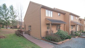 A two-story building with a flat roof and a covered porch. There is a gravel driveway and a wooden deck leading to the entrance.