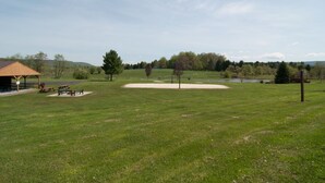 A park with picnic tables, a covered pavilion, a sand area, and a pond. - Deerfield Village 120 (Davis)