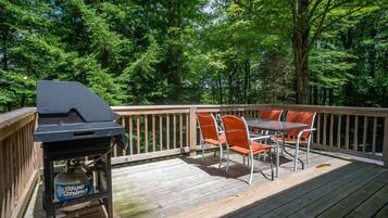 A deck with a grill, a table, and chairs.