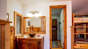 A wooden bathroom with a large mirror, a wooden sink, and a wooden cabinet. - Dancing Bear (Davis)