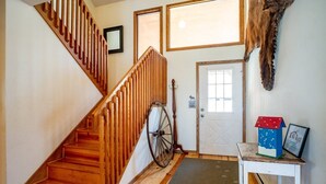 A wooden staircase with a handrail, a door with a window, a wall-mounted mirror, and a small table with a decorative box and a framed certificate. - Dancing Bear (Davis)