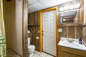 Une salle de bain avec une porte en bois, des toilettes, un lavabo et un miroir.