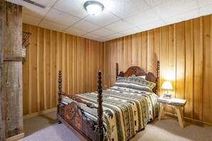 Une chambre à coucher aux murs lambrissés, avec un lit à baldaquin, une lampe de chevet et une étagère fixée au mur.