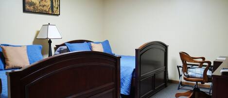 A bedroom with a bed, a desk, a chair, and a painting on the wall.