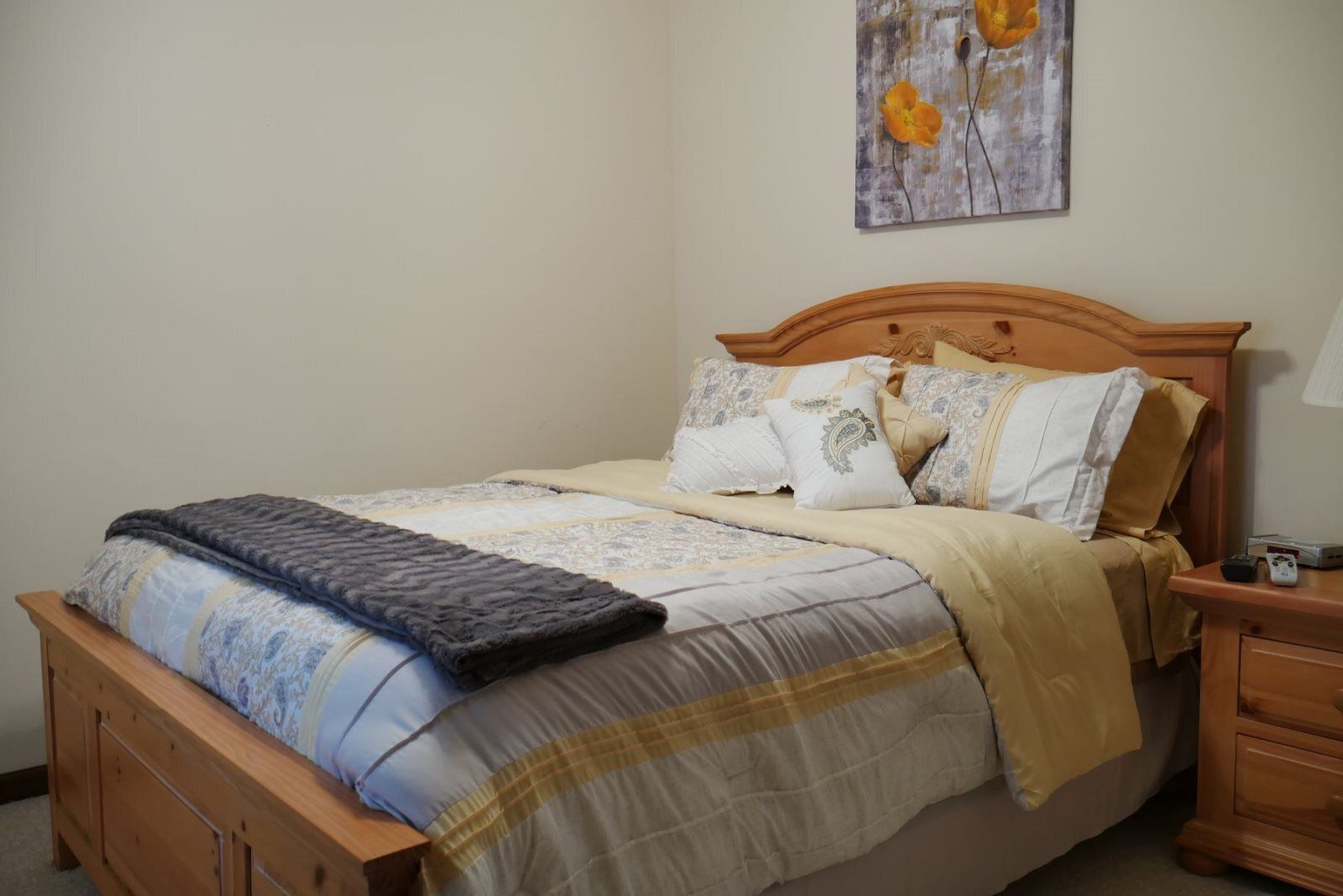 A neatly made bed with a patterned bedspread, multiple pillows, and a blanket.