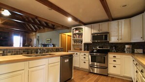 A kitchen with white cabinets, stainless steel appliances, and wooden beams on the ceiling. - Coire Taigh (Davis)