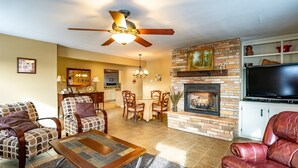 A living room with a fireplace, a ceiling fan, and a TV. - Coire Taigh (Davis)