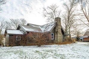 A rustic house with a stone chimney, surrounded by snow-covered ground and leafless trees. - Coire Taigh (Davis)