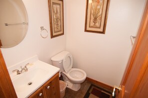 A small bathroom with a toilet, sink, and framed pictures on the wall.