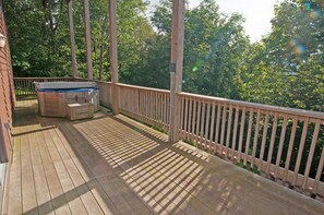 A wooden deck with a hot tub and a wooden railing.