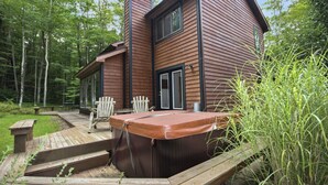 A cabin with a hot tub, wooden deck, and two Adirondack chairs. - Chamonix (Davis)