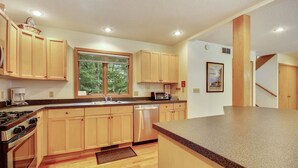 A modern kitchen with wooden cabinets, a built-in oven, a dishwasher, and a granite countertop. - Chamonix (Davis)