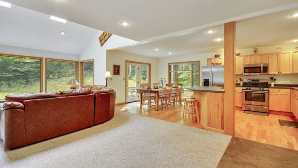 A modern kitchen with wooden cabinets, stainless steel appliances, and a dining area with a wooden table and chairs. - Chamonix (Davis)
