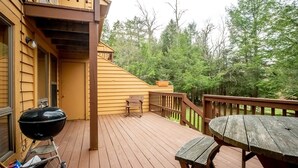 A wooden deck with a barbecue grill, a bench, and a table. - Deerfield Village 106 (Davis)