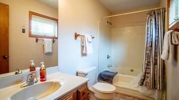 A bathroom with a large sink, toilet, and shower.