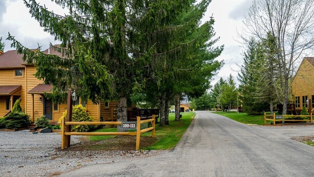 A rural road with a wooden fence and a sign indicating a property number. - Deerfield Village 106 (Davis)