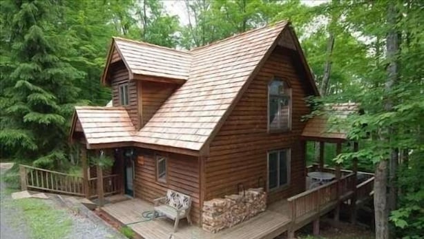 Eine Holzhütte mit geneigtem Dach, einer Veranda und einer Terrasse.