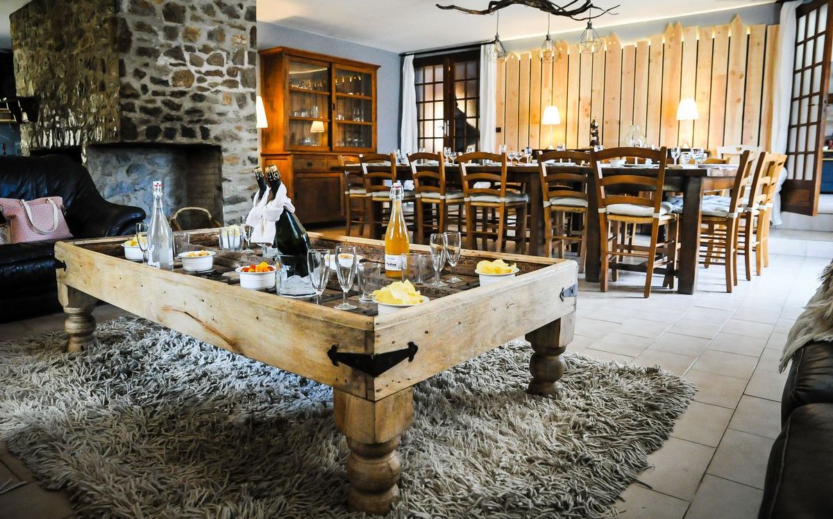 Uma sala de estar acolhedora com lareira de pedra, mesa de jantar de madeira e tapete macio.